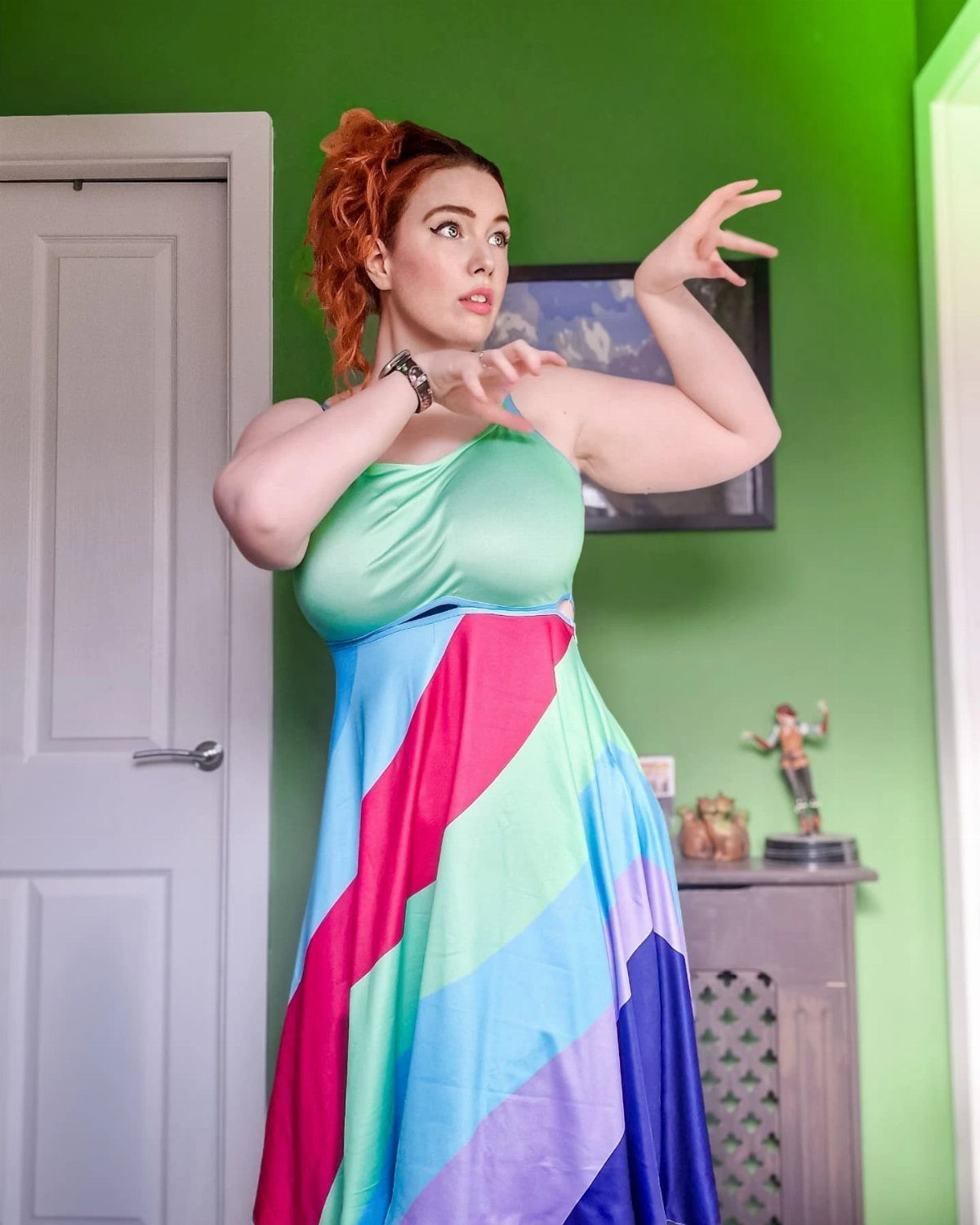 Woman with red hair wearing a colorful rainbow striped dress in a green room