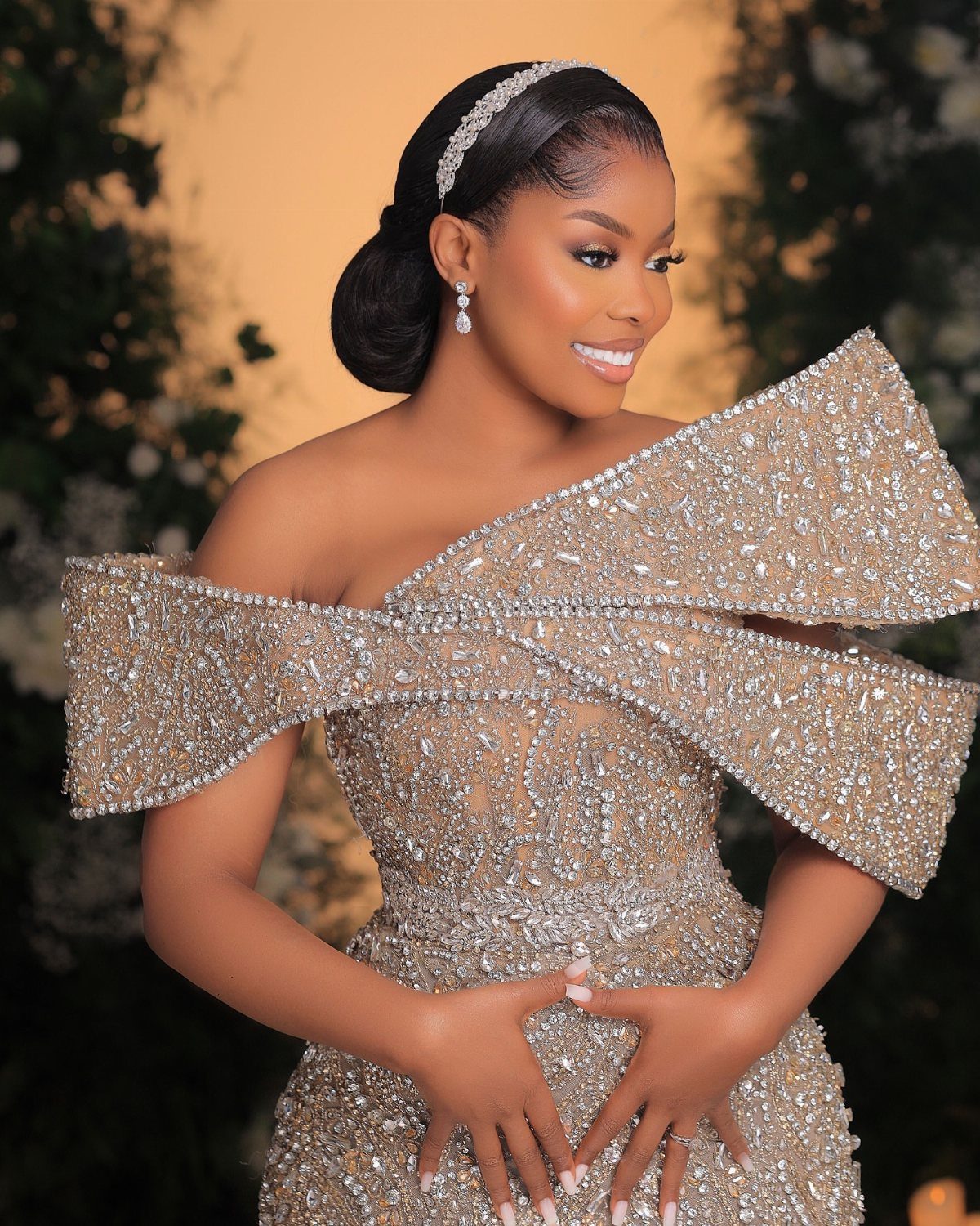 Woman in a sparkling champagne-colored off-the-shoulder reception dress with crystal embellishments.