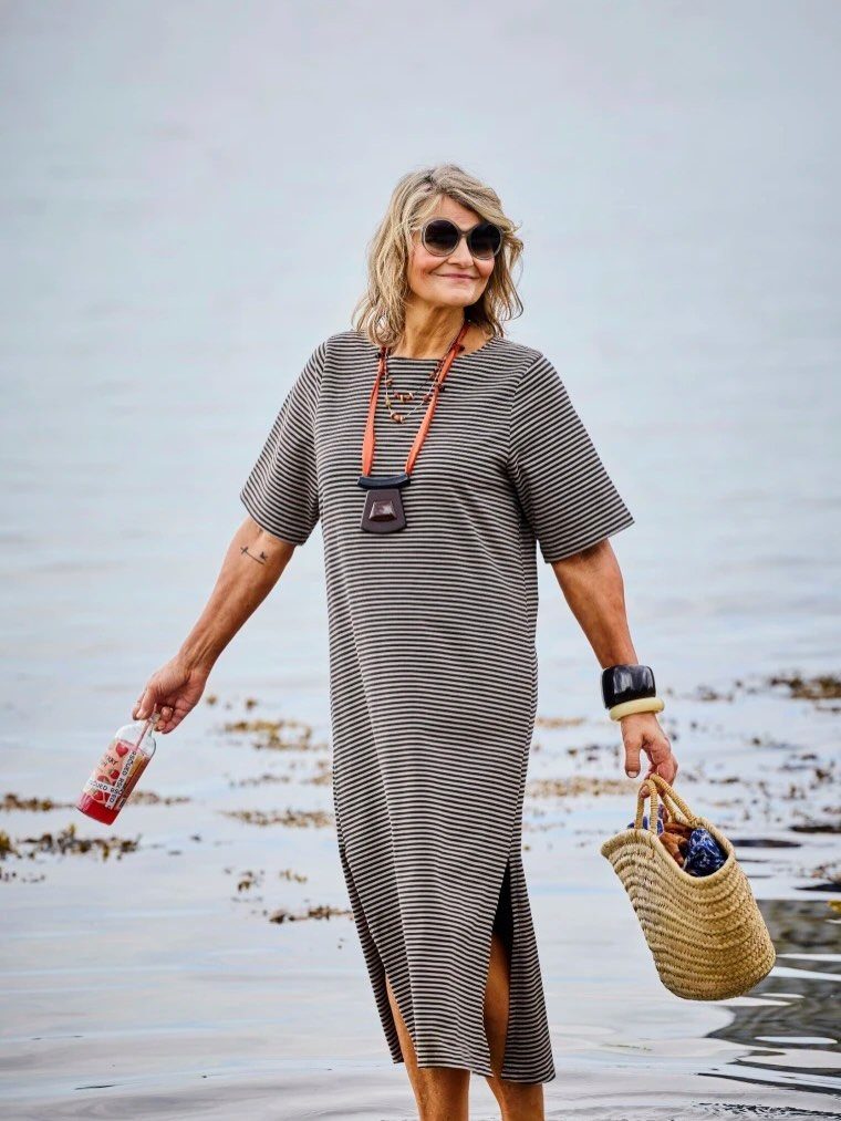 Mature woman wearing a striped midi dress and sunglasses on a sandy beach