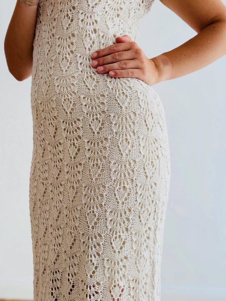 Cream crochet jumper dress with intricate lace patterns worn by a woman.