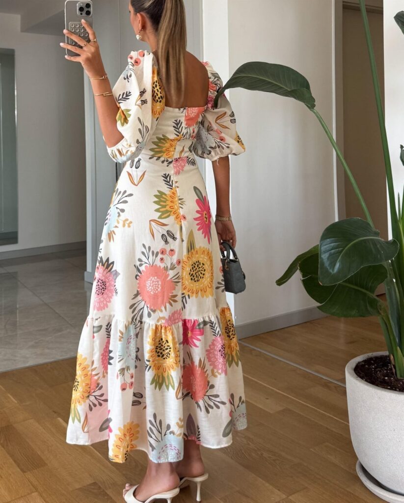 Woman wearing a white floral maxi dress with puffed sleeves and high heels.