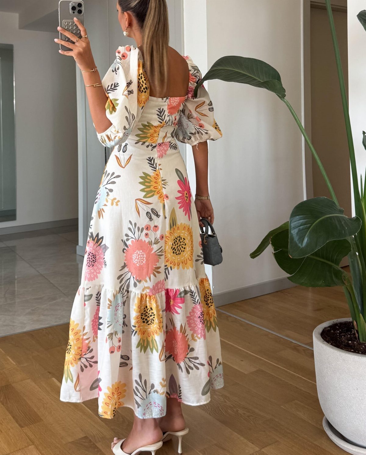 Woman wearing a white floral maxi dress with puffed sleeves and high heels.