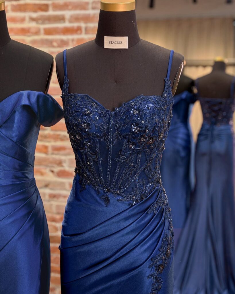 Royal blue prom dress with beaded bodice and draped skirt on a mannequin.