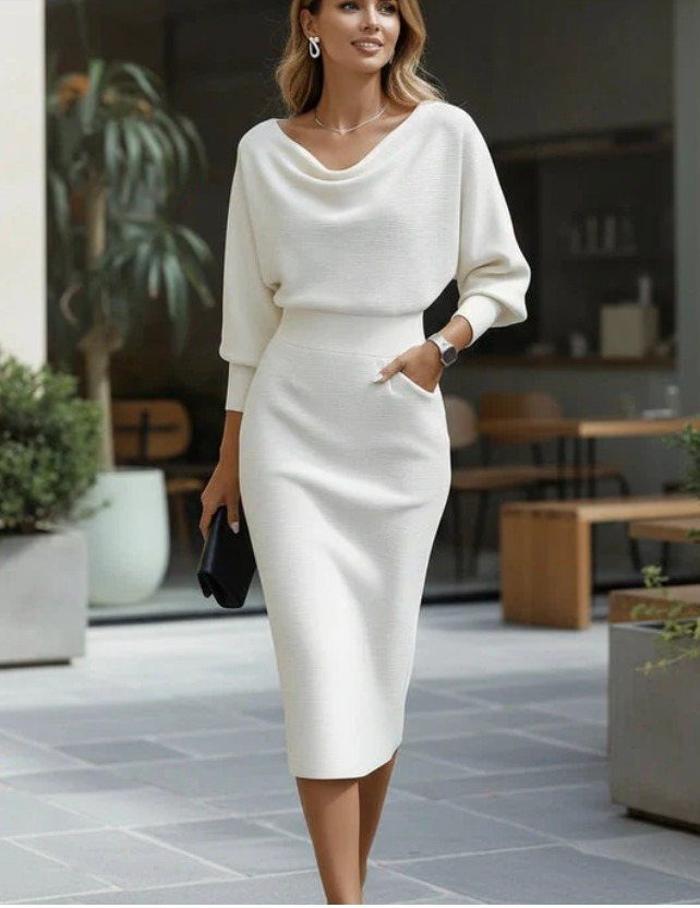 Woman wearing a white long-sleeved midi knit dress standing on a tiled patio.