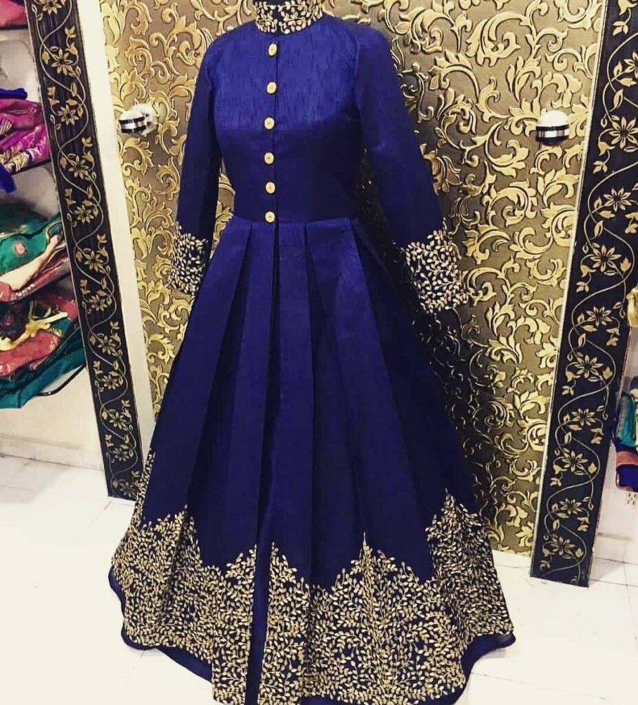 Royal blue long-sleeved gown with gold buttons and gold floral embroidery at the hem.