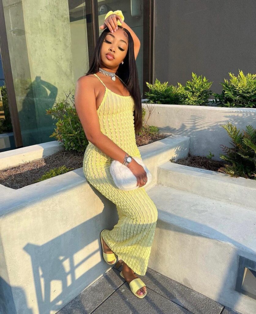 Woman in a yellow ribbed maxi dress and matching sandals posing outdoors.