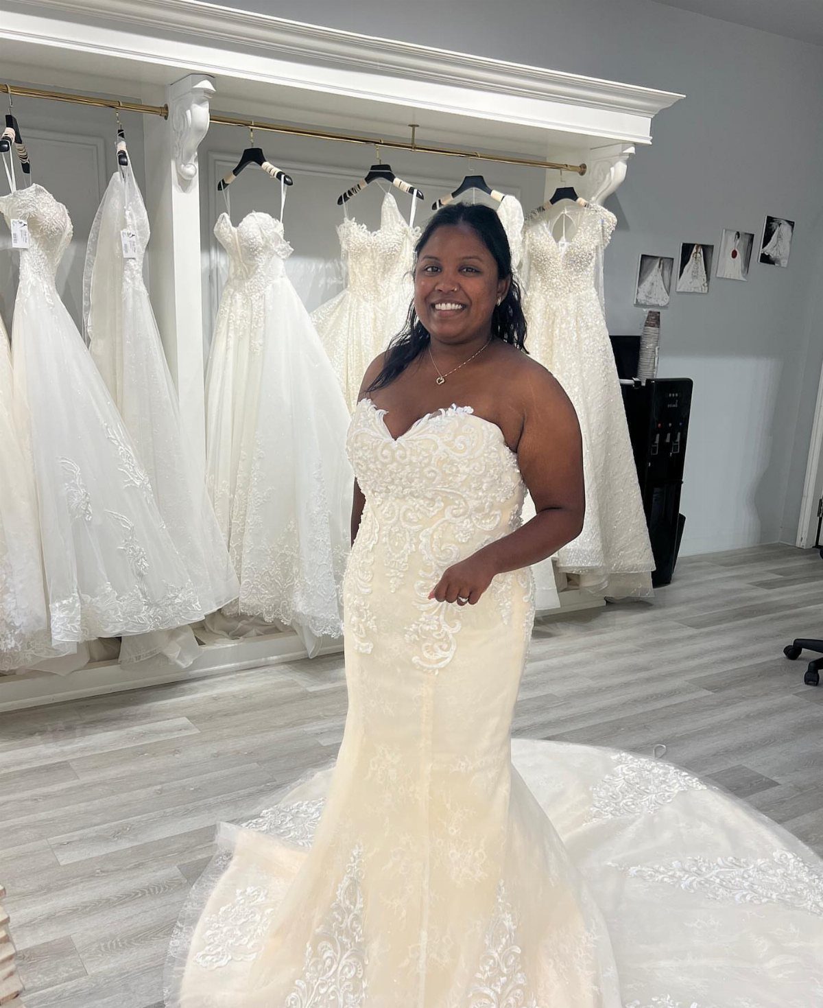 Woman in a lace wedding gown posing inside a bridal dress boutique.